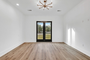 A nice master bedroom with french doors leading outdoors. The bedroom also has custom lighting and hardwood floors.