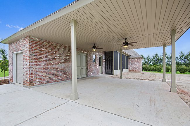 Brick floor carport that has plenty of space for storage and vehicles. Covered parking with two ceiling fans. Small garage door that leads into storage area. Covered area that leads to the door to the main house.