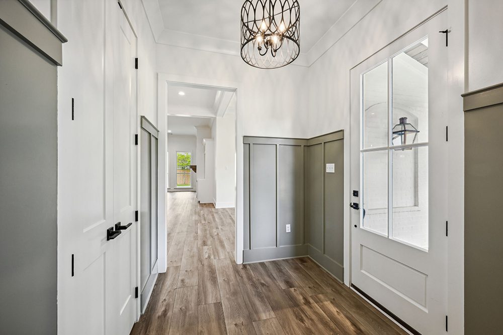 1-5048 Twin River Painted Frame Paneling This inviting entryway features elegant wainscoting in a soft green hue, complementing the white walls and door.