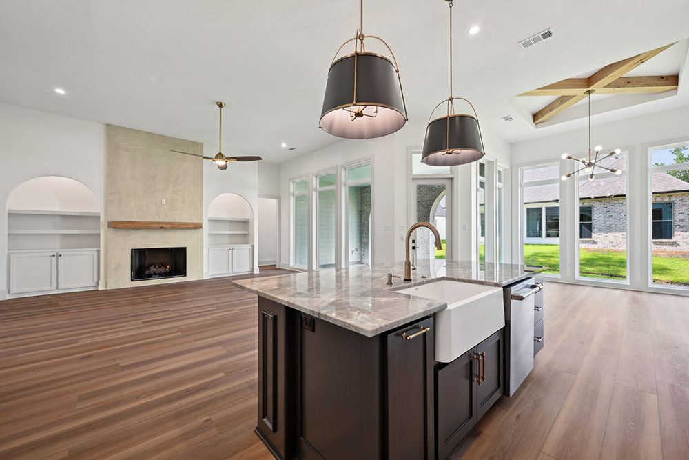 10-5040 Twin River View From Kitchen Built-in arched alcoves with cabinetry provide balance and storage while enhancing the room’s architectural interest. Tall ceilings and expansive windows line the right wall, bathing the space in natural light and creating a bright, inviting atmosphere. The layout offers effortless flow for everyday living and entertaining, blending luxury finishes with open, modern comfort.