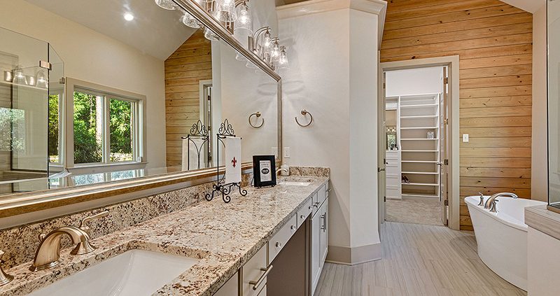 There is a shiplap accent wall that separates the master bathroom from the huge custom walk-in closet. Nice hard surface counters that are complimented by dual sinks.