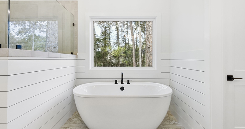 A large window offers a view of the serene, forested outdoors, complementing the bathroom's clean and peaceful design.