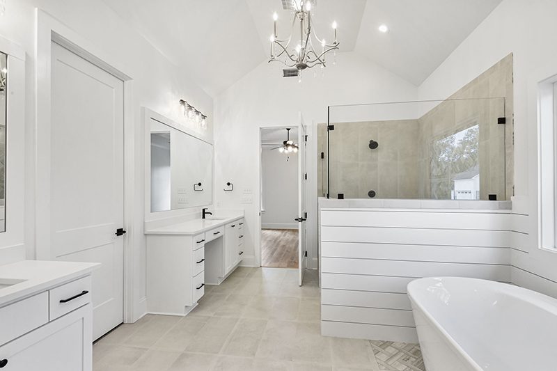 The room is finished with sleek white cabinetry, contrasting black handles and fixtures, and light-colored tiled flooring, creating an elegant and airy atmosphere.