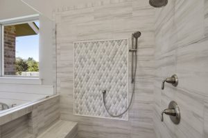 Beautiful custom tile work in the walk-shower that also features a bench. The walk-in shower is located in the master bathroom of this custom built home.