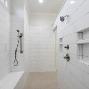 This walk-in, primary, walk-in shower is custom-designed with tile walls and flooring.