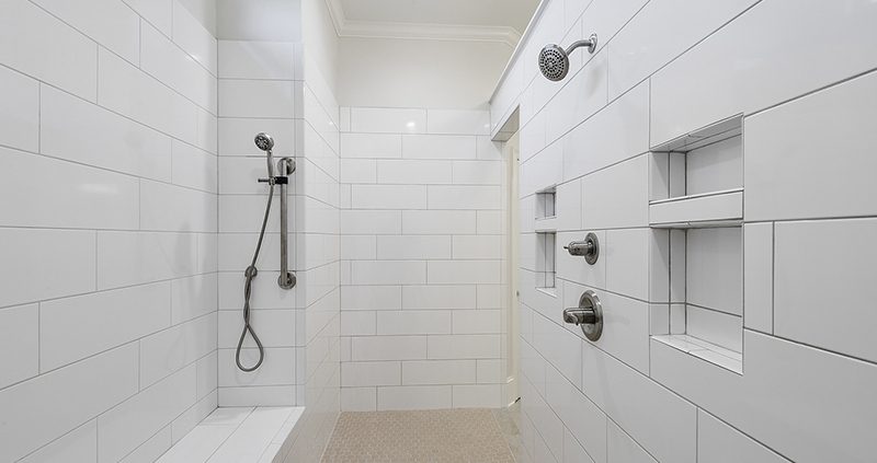 This walk-in, primary, walk-in shower is custom-designed with tile walls and flooring.