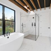 This master bathroom is unique with custom wood ceiling beams and a large window that lets in the light over the stand alone soaking tub.