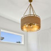 This sophisticated pendant light makes a bold yet balanced statement with its double-drum design. A warm, woven fabric exterior encircles a rich gold interior, casting a soft, golden glow that elevates the ambiance of the room.