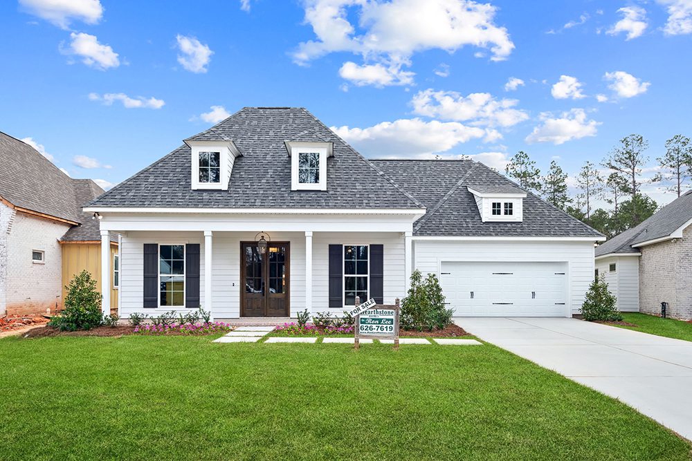 Exterior View Night Heron This image showcases a beautifully designed single-story home with a manicured lawn and a concrete driveway leading to a two-car garage.