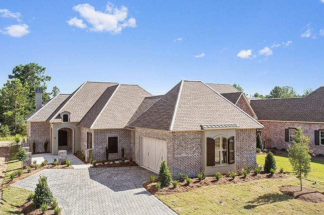 Overview of the exterior of this pristine home that is fully landscaped. The exterior features brick and custom shutters.