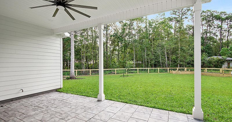 A covered patio that has a nice tile stone looking flooring.