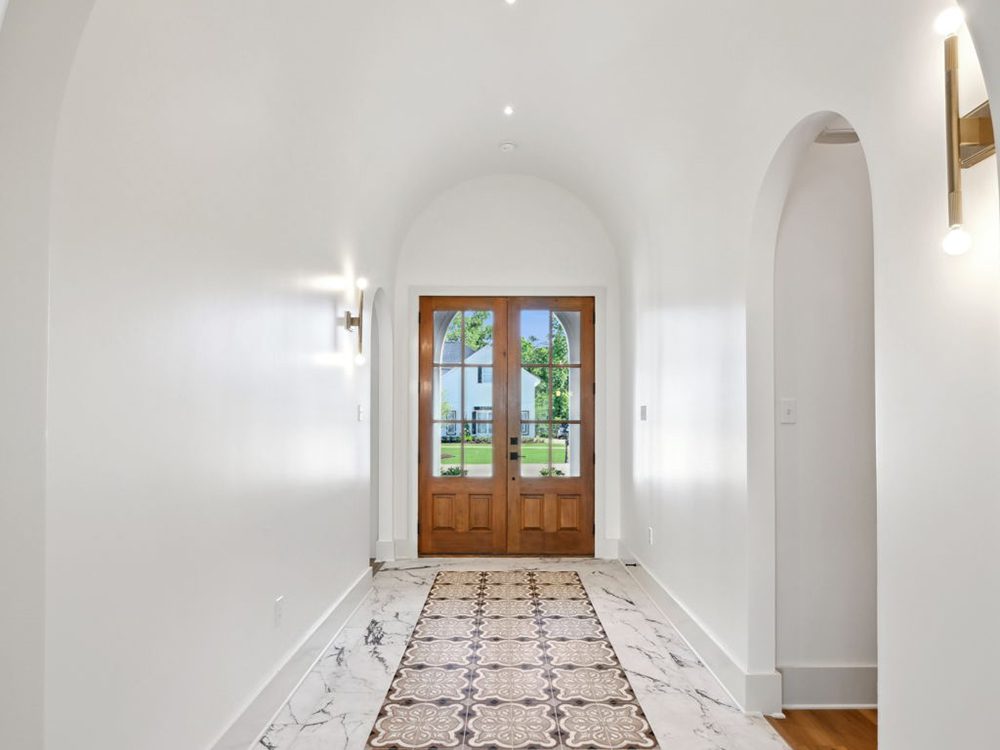 3-5040 Twin River Custom Foyer Flooring The patterned tile inlay creates a striking runway effect, bordered by marble-look tile that adds a refined, luxurious contrast.