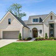 A dormer window above the entry adds charm and natural light to the upper level, while the oversized two-car garage provides ample space and convenience. The home’s thoughtful design balances traditional warmth with contemporary elegance.