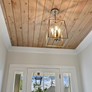 Real wood panel is used for the ship lap ceiling found in the foyer of this custom home.