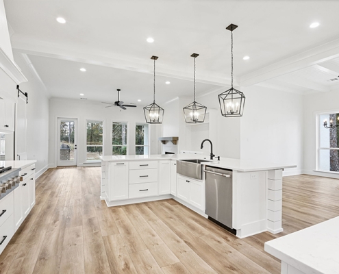 The image illustrates a spacious and bright kitchen featuring white cabinetry, a large island with a farmhouse sink, and elegant pendant lighting.